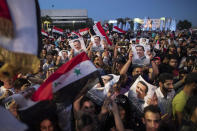 Syrian President Bashar Assad supporters hold up national flags and pictures of Assad as they celebrate at Omayyad Square, in Damascus, Syria, Thursday, May 27, 2021. (AP Photo/Hassan Ammar)