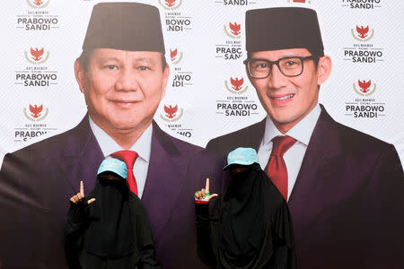 Women wearing full-face veil gesture next to a banner of presidential candidates Prabowo Subianto, and his running mate Sandiaga Uno, as they attend a campaign rally in Bandung, West Java province, Indonesia, March 28, 2019. REUTERS/Willy Kurniawan/Files