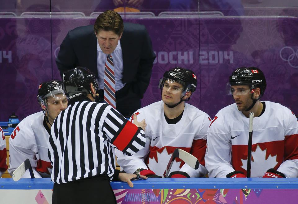 Canada coach Mike Babcock listens as an official explains the ruling on a goal that was disallowed during the third period of a men's quarterfinal ice hockey game against Latvia at the 2014 Winter Olympics, Wednesday, Feb. 19, 2014, in Sochi, Russia. The puck, which had partially crossed the Latvian goal line was pulled back by a Latvian player and was ruled dead. (AP Photo/Mark Humphrey)