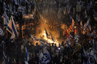 Israelis opposed to Prime Minister Benjamin Netanyahu's judicial overhaul plan set up bonfires and block a highway during a protest moments after the Israeli leader fired his defense minister, in Tel Aviv, Israel, Sunday, March 26, 2023. Defense Minister Yoav Gallant had called on Netanyahu to freeze the plan, citing deep divisions in the country and turmoil in the military. (AP Photo/Ohad Zwigenberg)