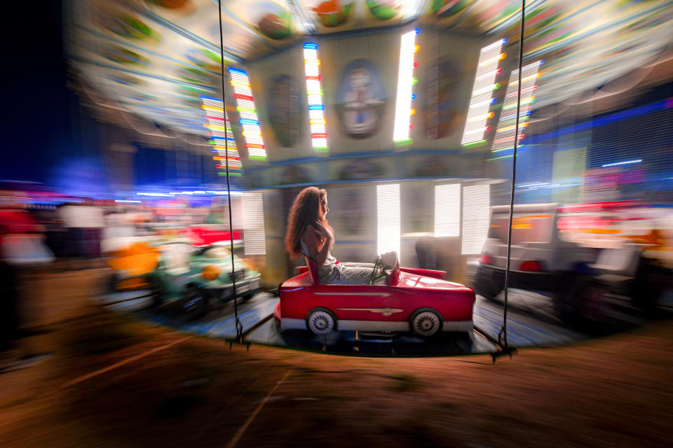 In this picture taken Saturday, Sept. 7, 2019, with a slow shutter speed, a little girl holds her hair while ridding in a merry go round at an autumn fair in Rosiorii de Vede, southern RomaniaRomania's autumn fairs are a loud and colorful reminder that summer has come to an end and, for many families in poorer areas of the country, one of the few affordable public entertainment events of the year. (AP Photo/Andreea Alexandru)