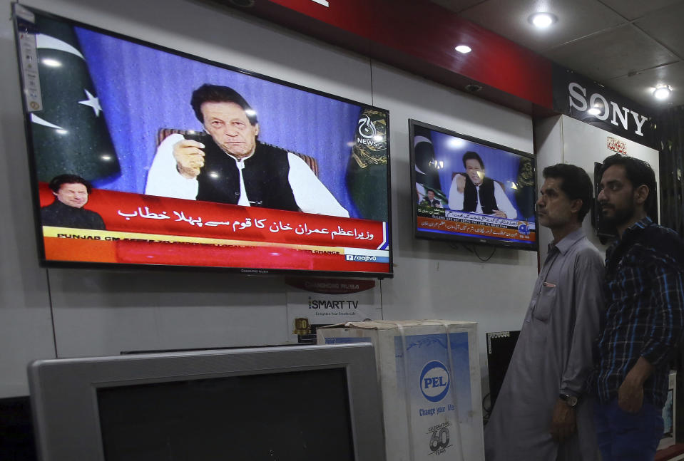 People watch a televised address of Pakistan's newly elected Prime Minister Imran Khan at an electronic shop in Karachi, Pakistan, Sunday, Aug. 19, 2018. Pakistan's newly elected prime minister Imran Khan Sunday said the country was in its worst economic condition and pledged to improve it by adopting austerity to cut government expenditure, introducing progressive taxation, end corruption and bringing back from abroad the plundered public money. (AP Photo/Fareed Khan)