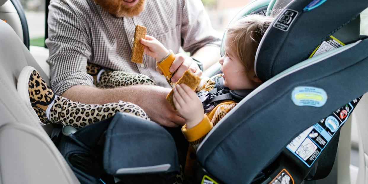dad strapping kid into car seat