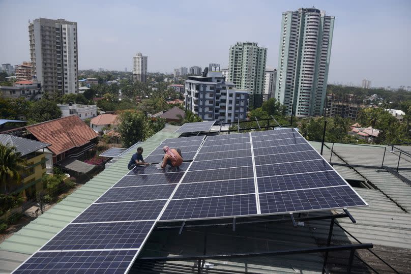 Workers install solar panels on the roof of a residential apartment in Kochi, southern Kerala state, India.