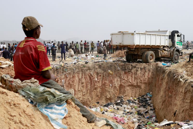 People await the discharge of expired AstraZeneca COVID-19 vaccines at the Gosa dump site in Abuja