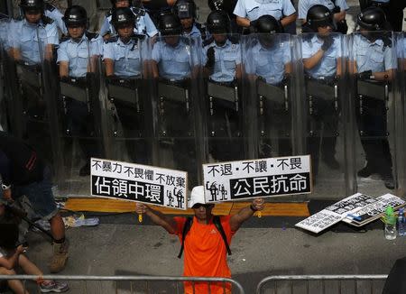 A protester holds up placards which reads "Occupy Central" (L) and "Civil Disobedience" in front of a line of riot police outside government headquarters in Hong Kong September 27, 2014. REUTERS/Bobby Yip