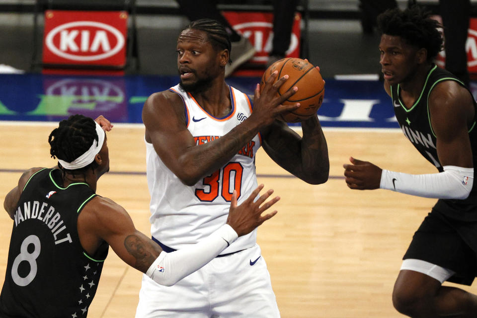 Julius Randle, center, of the New York Knicks looks to pass as Jarred Vanderbilt, left, and Anthony Edwards, right, of the Minnesota Timberwolves defend during the first half of an NBA basketball game Sunday, Feb. 21, 2021, in New York. (Sarah Stier/Pool Photo via AP)