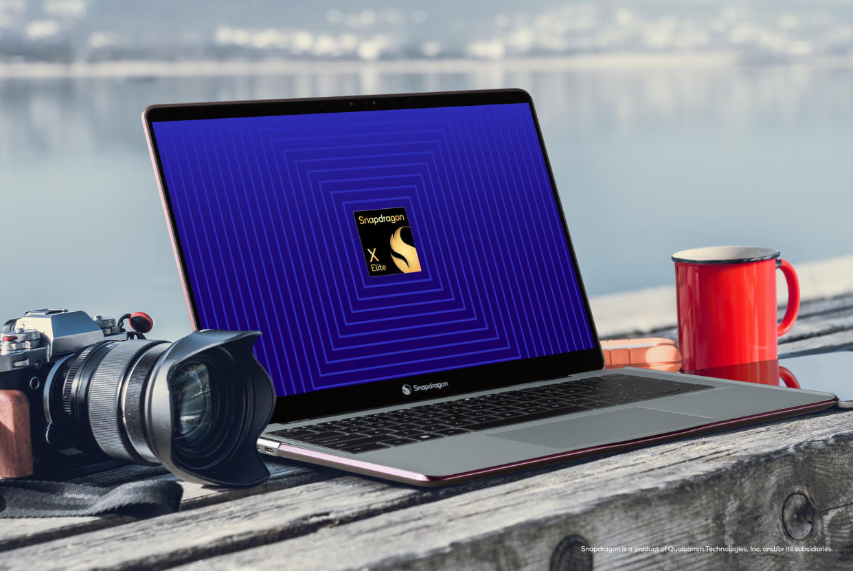  Qualcomm Snapdragon X Elite reference design laptop on a bench with a camera and coffee mug. 