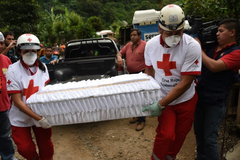 Members of the Red Cross carry a small coffin with the remains of a victim pulled out of the debris in the village of El Cambray II, some 15 km east of Guatemala City, on October 3, 2015