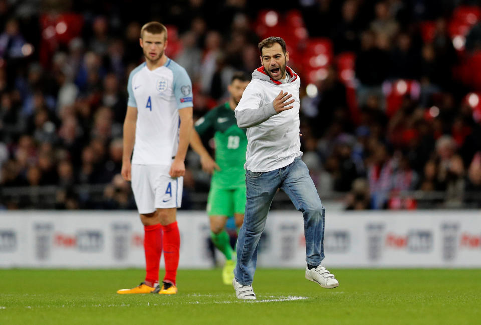 No laughing matter: England’s Eric Dier looks on as a pitch invader rushes past