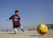 Five year-old Murtaza Ahmadi, an Afghan Lionel Messi fan, wears a shirt signed by Barcelona star Lionel Messi, as he plays football at the open area in Kabul, Afghanistan February 26, 2016. REUTERS/Omar Sobhani