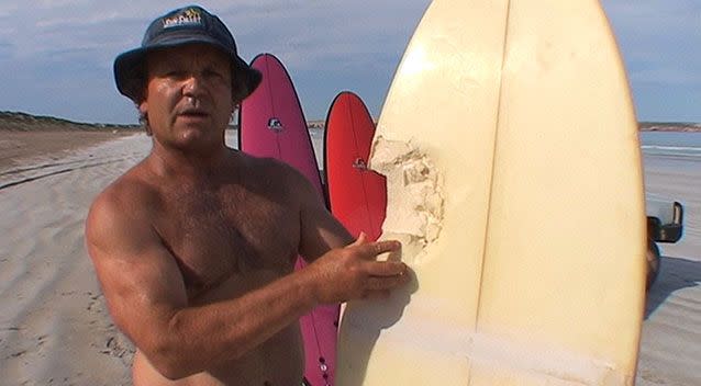 Shark attack victim John Campion shows the bite mark in his surfboard. Photo: 7News.