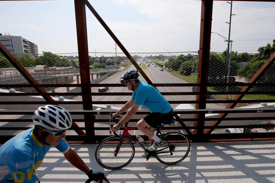 People ride across a pedestrian bridge over Northwest Expressway after the opening for the new bridge in Oklahoma City, Wednesday, June 7, 2023. The 121-foot pedestrian bridge that spans Northwest Expressway near Wilshire, connects the Hefner/Overholser Trail in Oklahoma City. 