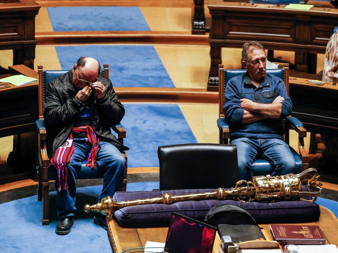 Edward Ambrose, left, wipes away a tear as he and Richard Beauvais, right, who were switched at birth in 1955, listen to Manitoba Premier Wab Kinew apologize in the legislature on Thursday. (John Woods/The Canadian Press - image credit)