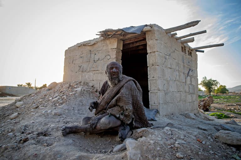 (FILES) In this file photo taken on December 28, 2018 Amou Haji (uncle Haji) sits in front of an open brick shack that the villagers constructed for him, on the outskirts of the village of Dezhgah in the Dehram district of the southwestern Iranian Fars province. - An Iranian dubbed the 