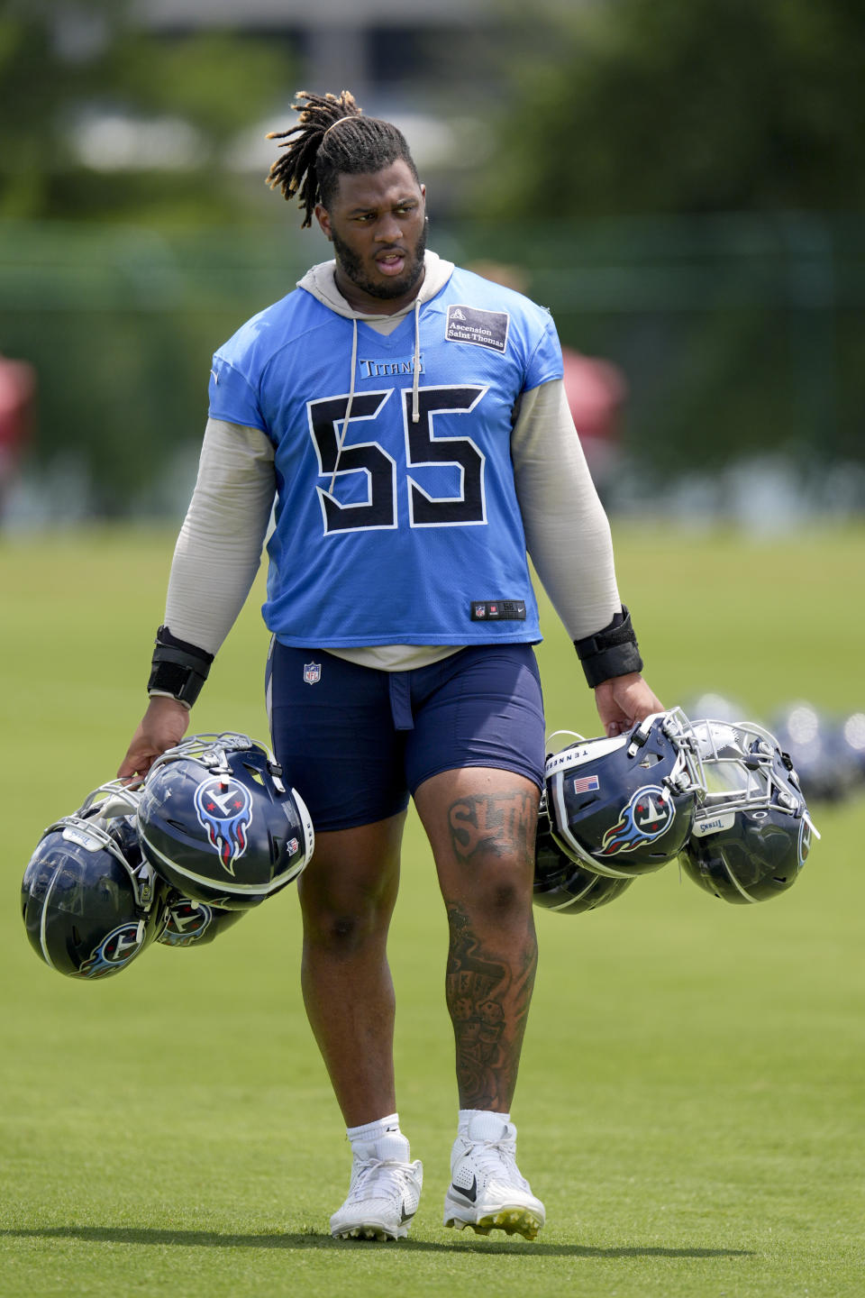 Tennessee Titans tackle JC Latham (55) walks off the field carrying teammates helmets after NFL football practice Wednesday, June 5, 2024, in Nashville, Tenn. (AP Photo/George Walker IV)