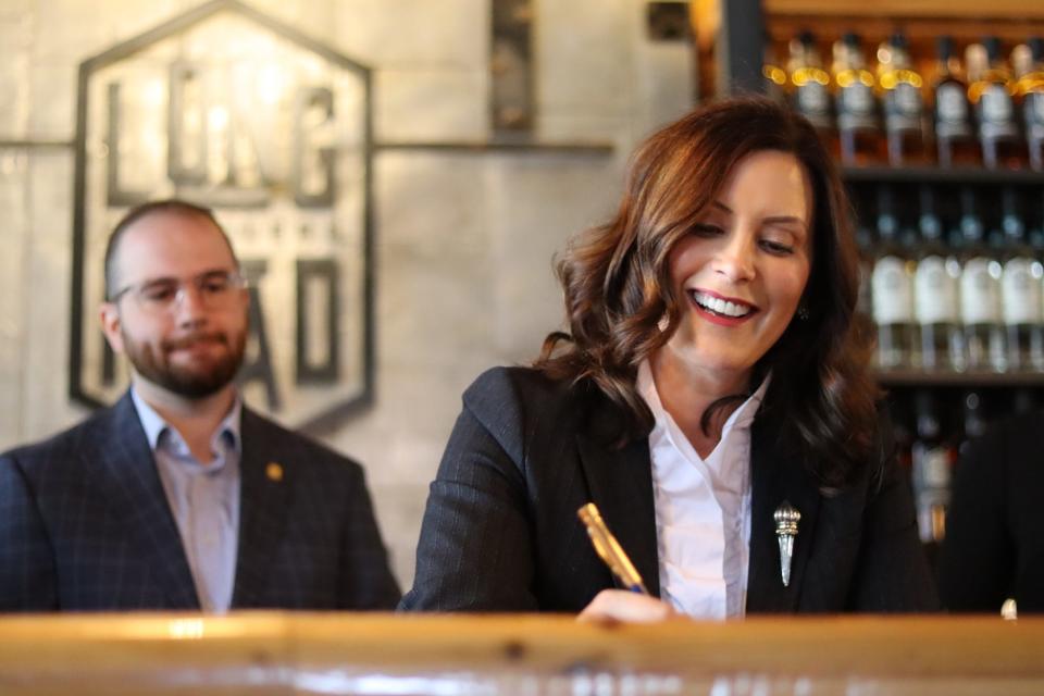 Michigan Sen. Jeremy Moss, D-Southfield, stands behind Gov. Gretchen Whitmer during a bill signing at Long Road Distillers in Grand Rapids.