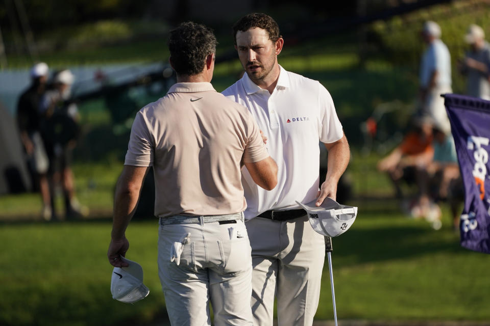 Patrick Cantlay, right, shakes hands with Rory McIlroy on the 18th green during the final round of the St. Jude Championship golf tournament Sunday, Aug. 13, 2023, in Memphis, Tenn. (AP Photo/George Walker IV)