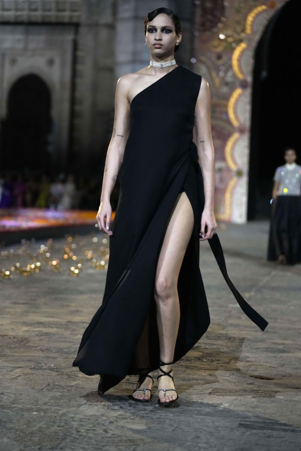 A model wears a creation for the Dior Pre-Fall 2023 collection at the Gateway of India landmark monument in Mumbai, India, Thursday, March 30, 2023. (AP Photo/Rafiq Maqbool)