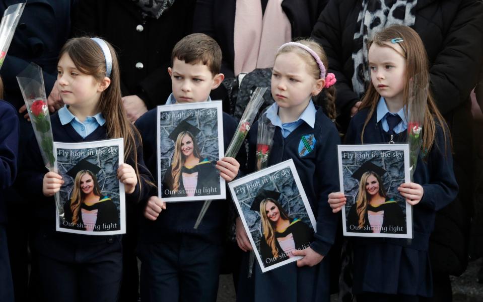 Pupils from Ashling Murphy's class hold photographs of her and red roses outside St Brigid's Church - Damien Eagers 