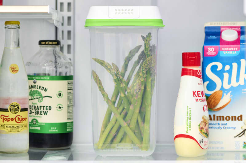 head on shot of asparagus in a plastic container in a fridge.