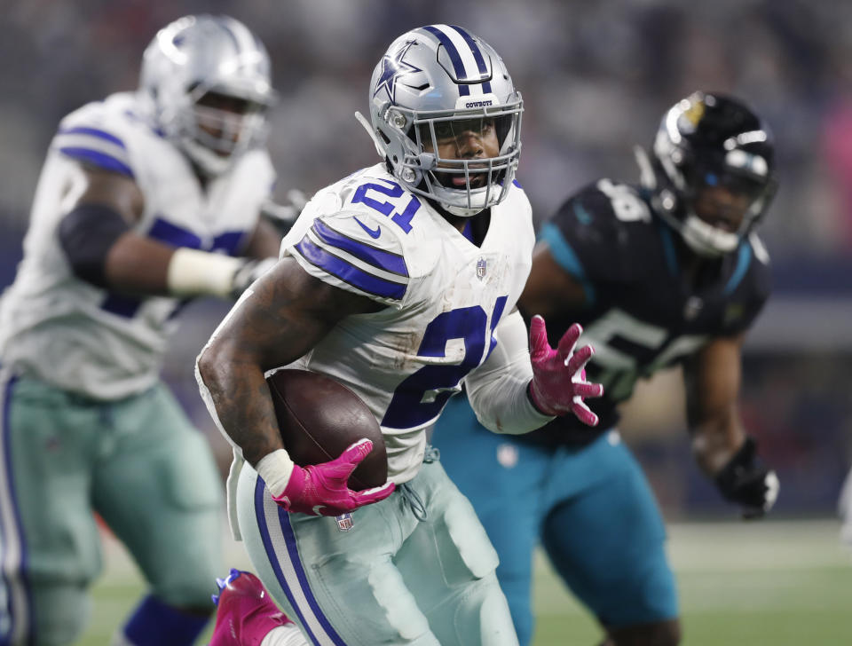 FILE - In this Oct. 14, 2018 file photo Dallas Cowboys running back Ezekiel Elliott (21) carries past Jacksonville Jaguars defensive end Dante Fowler (56) into the end zone for a touchdown in the second half of an NFL football game in Arlington, Texas. Elliott has been waiting for another Thanksgiving game since he had to miss last year on his six-game suspension over domestic violence allegations. In his Thanksgiving debut against the Redskins two years ago as a rookie, he jumped into the giant Salvation Army red kettle after a touchdown in a 31-26 Dallas win. The Cowboys can tie the Redskins for the NFC East lead on Thursday, Nov. 22, 2018 with five games remaining. (AP Photo/Jim Cowsert, file)