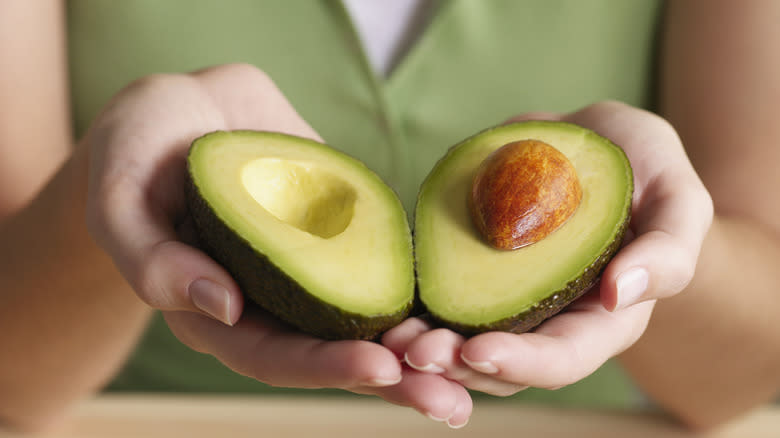 Hands holding sliced avocado