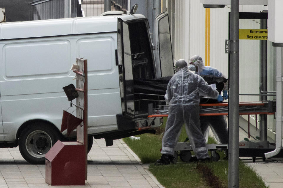 FILE In this file photo taken on Tuesday, April 28, 2020, Medical workers carry a body to a vehicle from the hospital for coronavirus patients in Kommunarka, outside Moscow, Russia. Russia's updated statistics on coronavirus-linked deaths showed that over 100,000 people with COVID-19 had died in the pandemic by December, a number much higher than previously reported by government officials. According to the data released Monday Dec. 28, 2020, by Russia's state statistics agency, Rosstat, a total of 116,030 people with COVID-19 died in Russia between April and November. The count included cases where the virus was not the main cause of death and where the virus was suspected but not confirmed. (AP Photo/Pavel Golovkin, File)