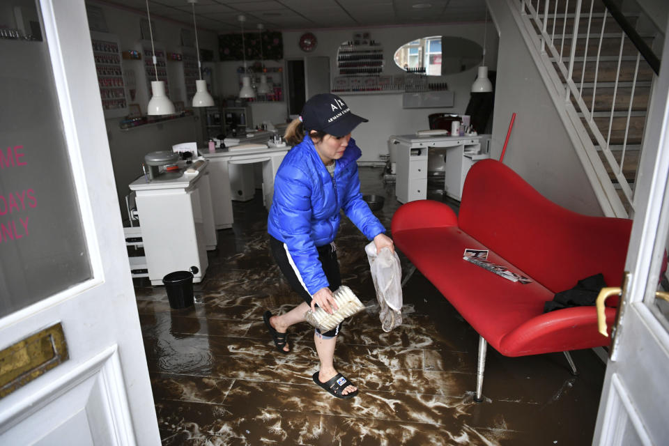 An employee cleans a nail salon, after Storm Dennis hits the UK leading to widespread flooding, in Pontypridd, Wales, Sunday, Feb. 16, 2020. Storm Dennis roared across Britain with high winds and heavy rains Sunday, prompting authorities to issue some 350 flood warnings, including a “red warning" alert for life-threatening flooding in south Wales. (Ben Birchall/PA via AP)