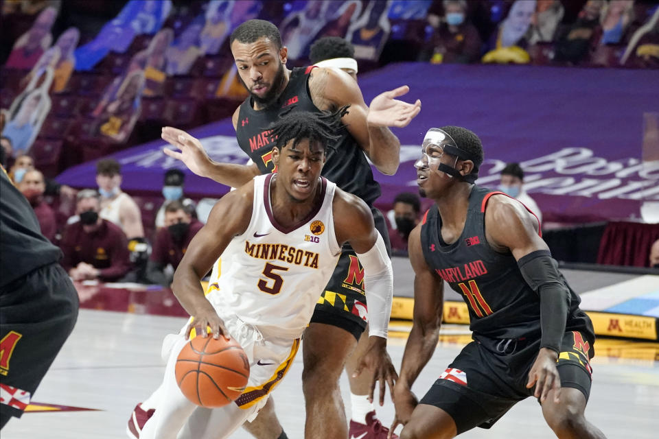 Minnesota's Marcus Carr (5) drives around Maryland's Darryl Morsell (11) and Galin Smith (30) in the first half of an NCAA college basketball game, Saturday, Jan. 23, 2021, in Minneapolis. (AP Photo/Jim Mone)