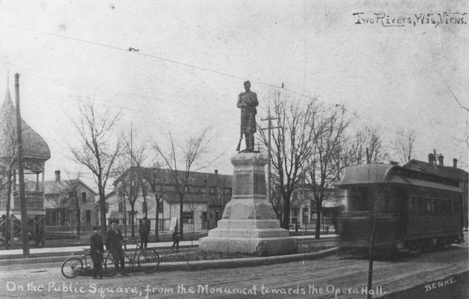 Electric streetcar passing the Civil War Soldiers Monument on Washington Street, Two Rivers, c.1904-1905. The first bandstand on the west side of Central Park and the old Opera House on 18th Street are visible in this Herman Benke postcard.