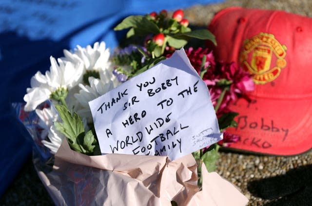 Tributes are laid in memory of Sir Bobby Charlton by The United Trinity statue at Old Trafford