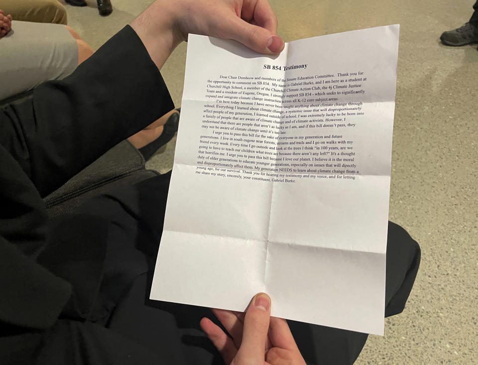 High school sophomore Gabriel Burke holds a printed copy of his testimony in support of an Oregon bill that would require climate change instruction in public schools from kindergarten through 12th grade, before testifying in a hearing at the state Capitol in Salem, Ore., Thursday, March 9, 2023. Burke said he drove more than an hour from Eugene in order to testify in person. (AP Photo/Claire Rush)