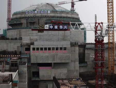 Workers (bottom) stand in front of a nuclear reactor as part of the Taishan Nuclear Power Plant seen under construction in Taishan, Guangdong province, October 17, 2013. REUTERS/Bobby Yip
