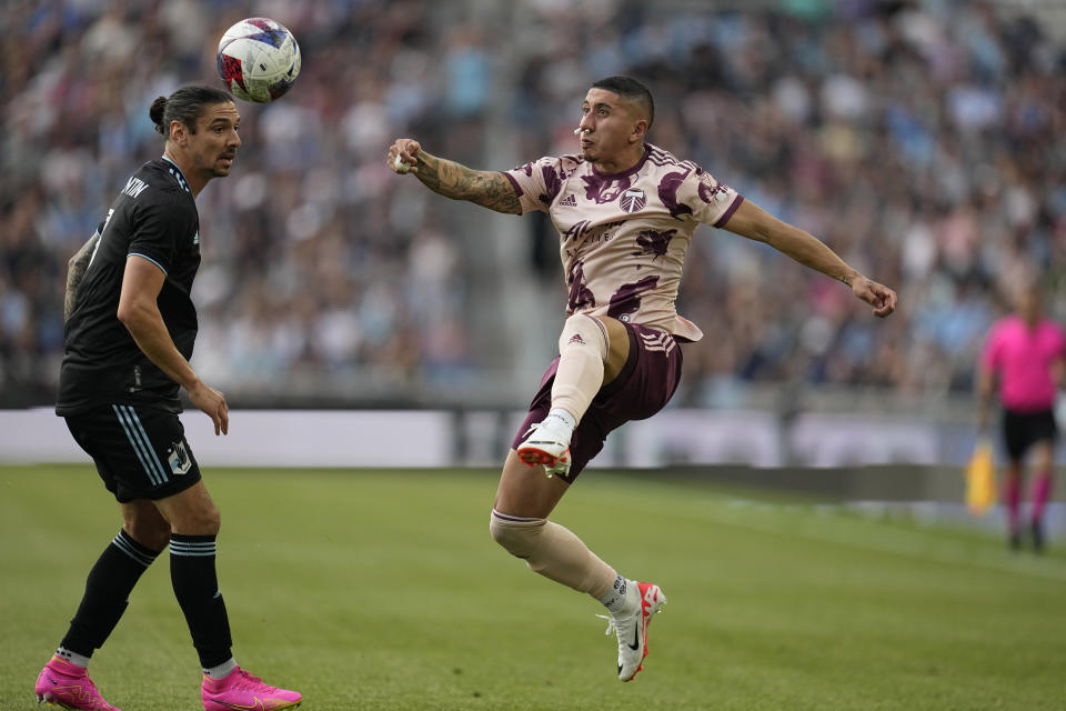 Portland Timbers midfielder Marvin Loría, right, jumps for possession against Minnesota United defender Zarek Valentin, left, during the first half of an MLS soccer match, Saturday, July 1, 2023, in St. Paul, Minn. (AP Photo/Abbie Parr)