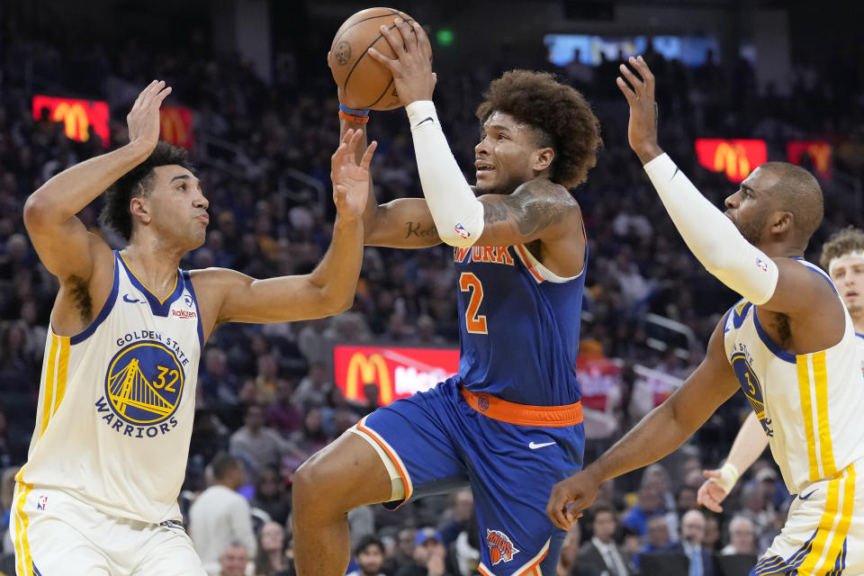 New York Knicks guard Miles McBride (2) shoots against Golden State Warriors forward Trayce Jackson-Davis (32) and guard Chris Paul, right, during the first half of an NBA basketball game in San Francisco, Monday, March 18, 2024. (AP Photo/Jeff Chiu)