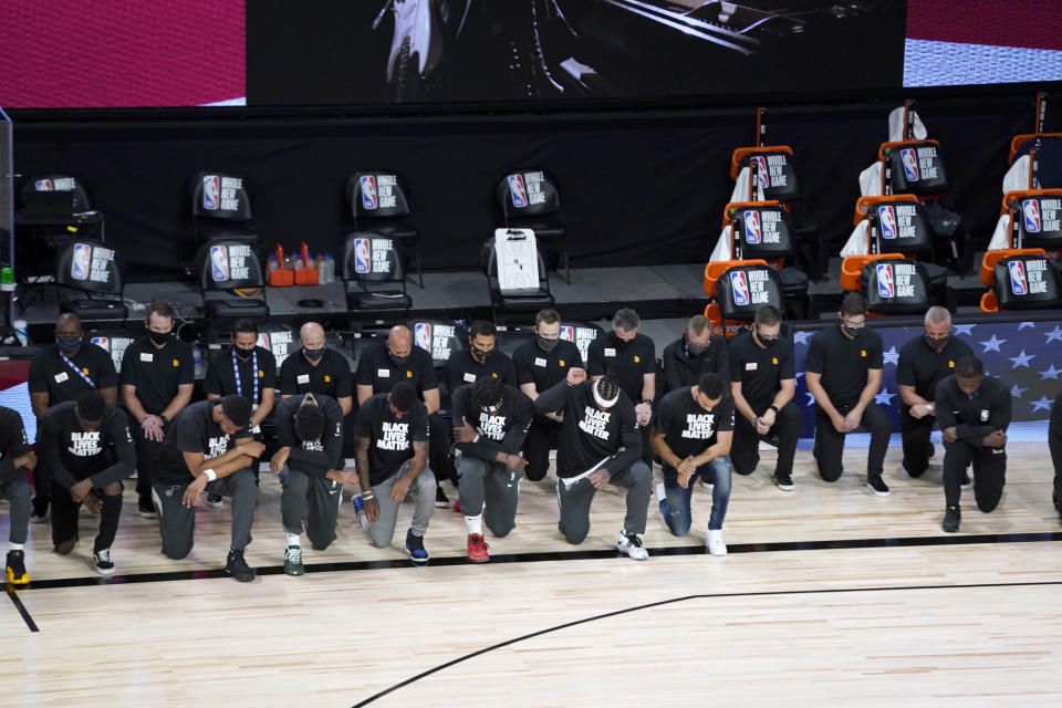 Jugadores y técnicos de los Pelicans y los Jazz y los árbitros del encuentro se arrodillan durante el himno de Estados Unidos. (Foto: Pool / Getty Images).