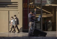 A lone street performer tunes his guitar on a mostly-empty Hollywood Boulevard in Los Angeles, Tuesday, March 24, 2020. New cases of the coronavirus surged around the state. (AP Photo/Damian Dovarganes)