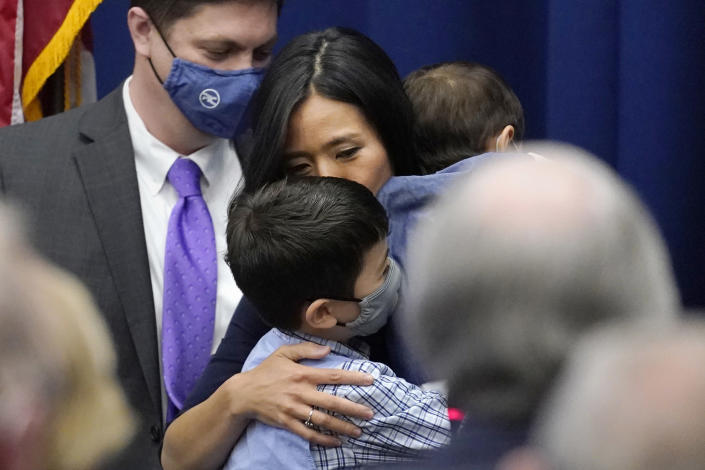 Michelle Wu kisses her son Blaise, while holding her son Cass, after she was sworn-in as Boston Mayor during a ceremony at Boston City Hall, Tuesday, Nov. 16, 2021, in Boston. The election of Wu marked the first time that Boston voters elected a woman, or a person of color, to lead the city. Before Wu, Boston had only elected white men as mayor. At rear left is Wu's husband Conor Pewarski. (AP Photo/Charles Krupa)