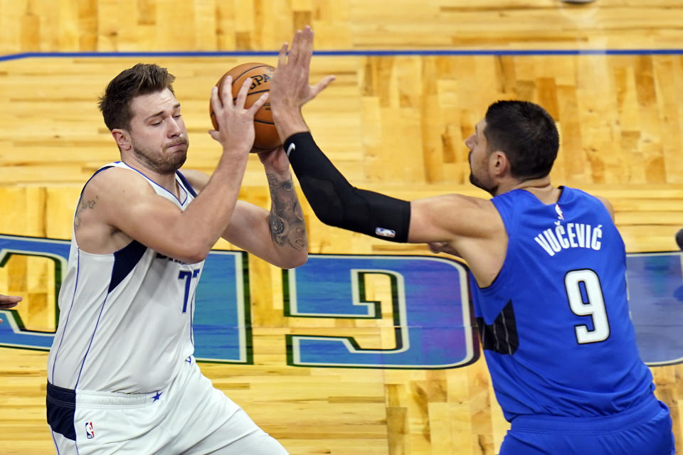 Dallas Mavericks guard Luka Doncic, left, moves to get past Orlando Magic center Nikola Vucevic (9) during the first half of an NBA basketball game, Monday, March 1, 2021, in Orlando, Fla. (AP Photo/John Raoux)