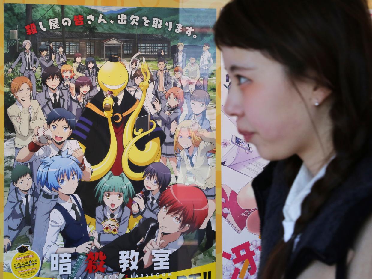 A woman walks past a poster of animation "Assassination Classroom" in Tokyo, Saturday, Jan. 31, 2015.