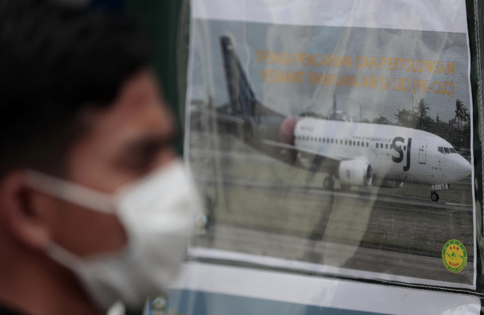 FILE - In this in this Jan. 10, 2021, file photo, a man walks past a picture of a Sriwijaya Air passenger jet that crashed off Java island, put up at the command center for the search and rescue mission at Tanjung Priok Port in Jakarta, Indonesia. A malfunctioning automatic throttle may have caused the pilots of the Sriwijaya Air jet to lose control, leading to the plane's plunge into the Java Sea last month, Indonesian investigators said Wednesday, Feb. 10, 2021. (AP Photo/Dita Alangkara, File)