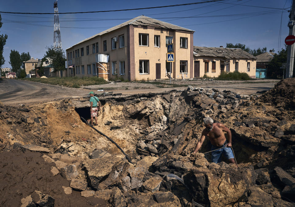 Local residents take water with an air bomb from a partially restored water supply in Bakhmut, Donetsk region, Ukraine, Wednesday, Aug. 31, 2022. (AP Photo/Kostiantyn Liberov)