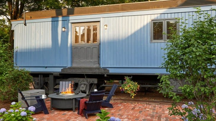 The Kent Collection's blue boxcar, with a fire pit outside