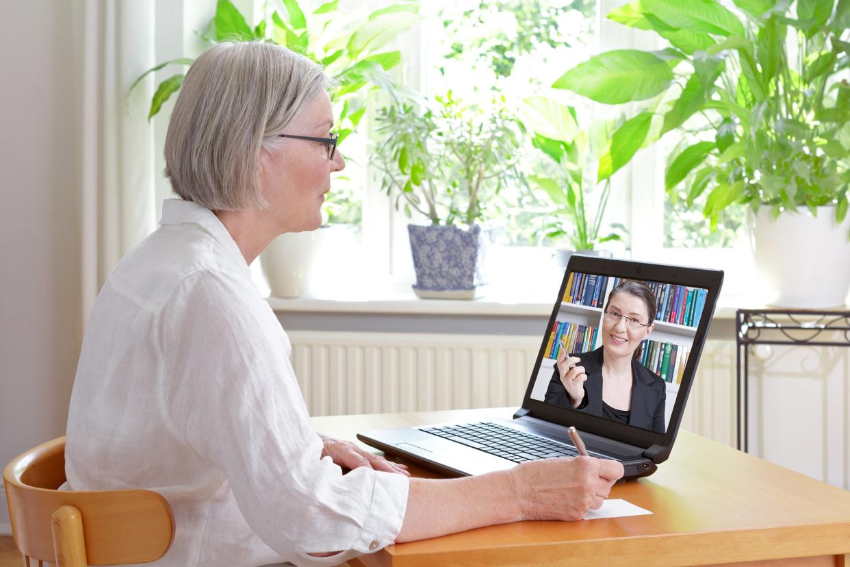 Senior woman at home in front of laptop watching an online video