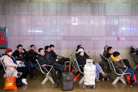 People watch the CCTV Spring Festival Gala TV show on a screen at the Beijing West train station in Beijing, China, January 15, 2018. REUTERS/Thomas Peter