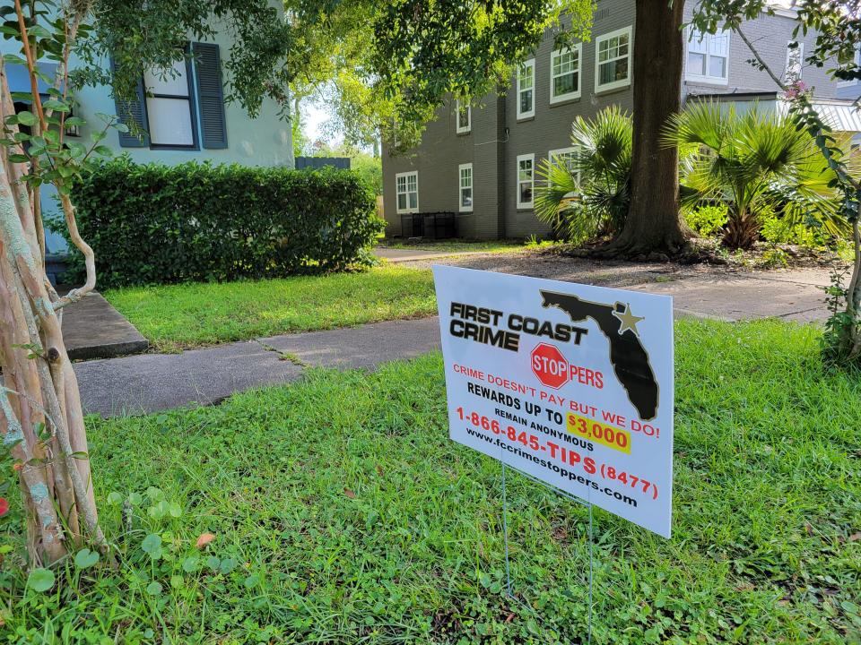 A First Coast Crime Stoppers sign offering a reward for information stands in front of the Myra Street home and driveway where Caroline Schollaert was shot and killed.