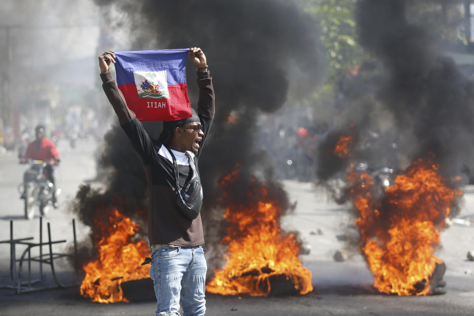 一名示威者1日在太子港要求總理亨利辭職的抗議活動中高舉海地國旗。（美聯社）