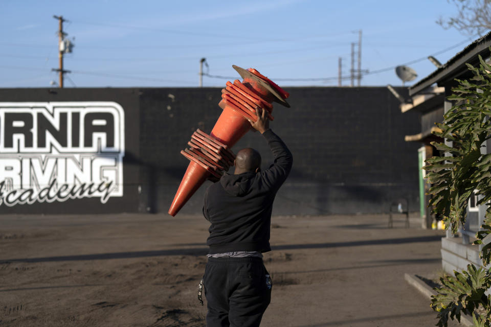 Student driver Stephen Gholar carries traffic cones after a class at California Truck Driving Academy in Inglewood, Calif., Wednesday, Nov. 17, 2021. Business is booming at a truck-driving academy in suburban Los Angeles amid a nationwide shortage of long-haul drivers. The California Truck Driving Academy in Inglewood has seen annual enrollment grow by almost 20% since last year. (AP Photo/Jae C. Hong)