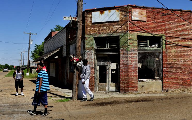 Young men in Drew, Miss., hang out on the street near a burned-out store painted with the designation “For Colored,” which dates to the era of segregation. (Photo: Michael S. Williamson/The Washington Post via Getty Images)